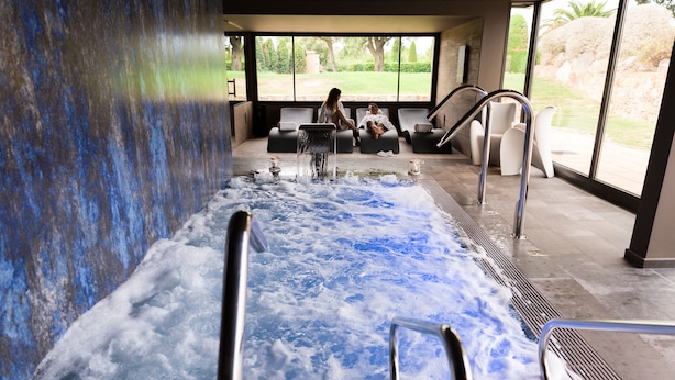 Spa-område med jacuzzi, siddepladser og udsigt til naturen.