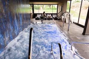 Un área de spa con hidromasaje, asientos y vistas al exterior.
