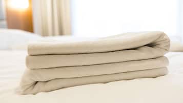 A neatly folded beige blanket on a bed.
