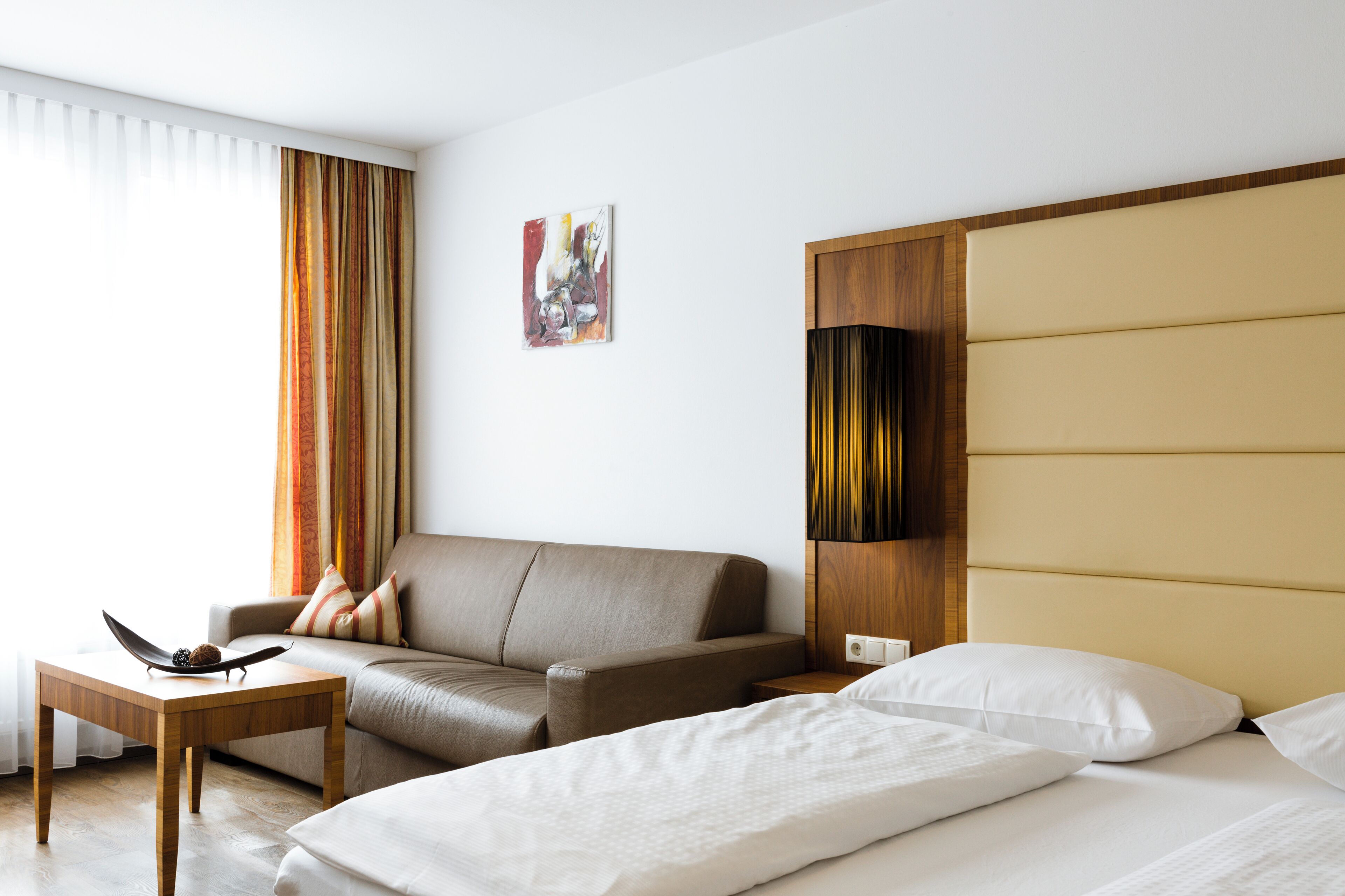 Una habitación de hotel con cama, sofá, mesita y un buró.