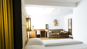 A hotel room with a bed, a desk, a sofa, and a painting on the wall. - Hotel Kapeller (Innsbruck)