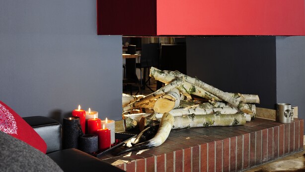 A fireplace with logs, candles, and a carved animal head. - Hotel Kapeller (Innsbruck)
