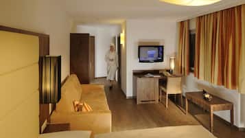A hotel room with a sofa, a TV, a desk, and a wooden cabinet.