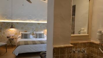 A bedroom with a bed, bedside table, lamp, and a ceiling fan.