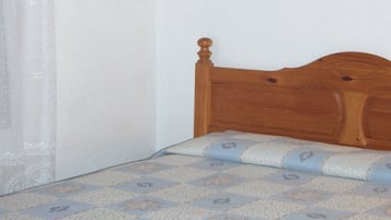 A single bed with a wooden headboard and a patterned bedspread.