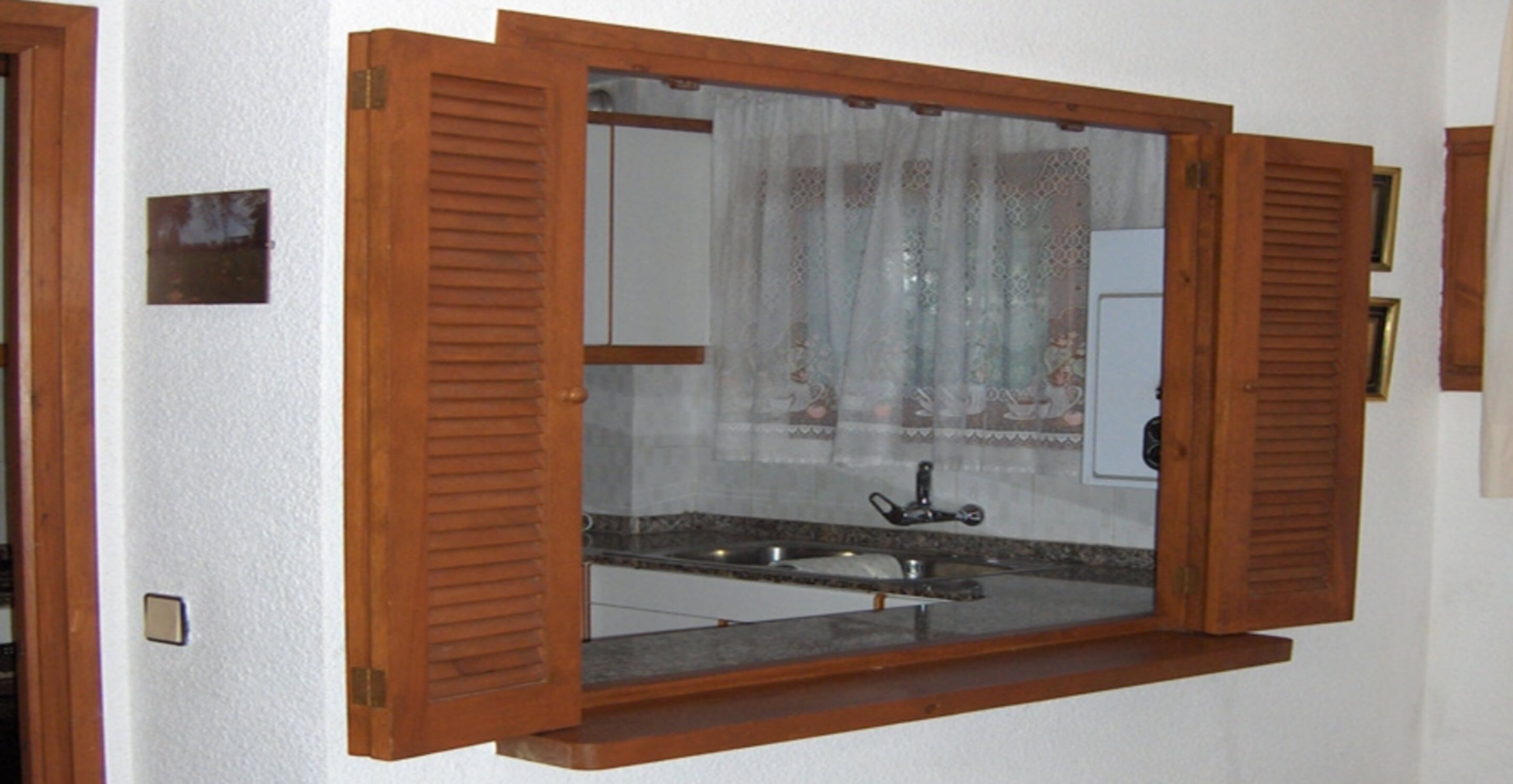 A bathroom with a wooden-framed window, a sink, and a mirror.