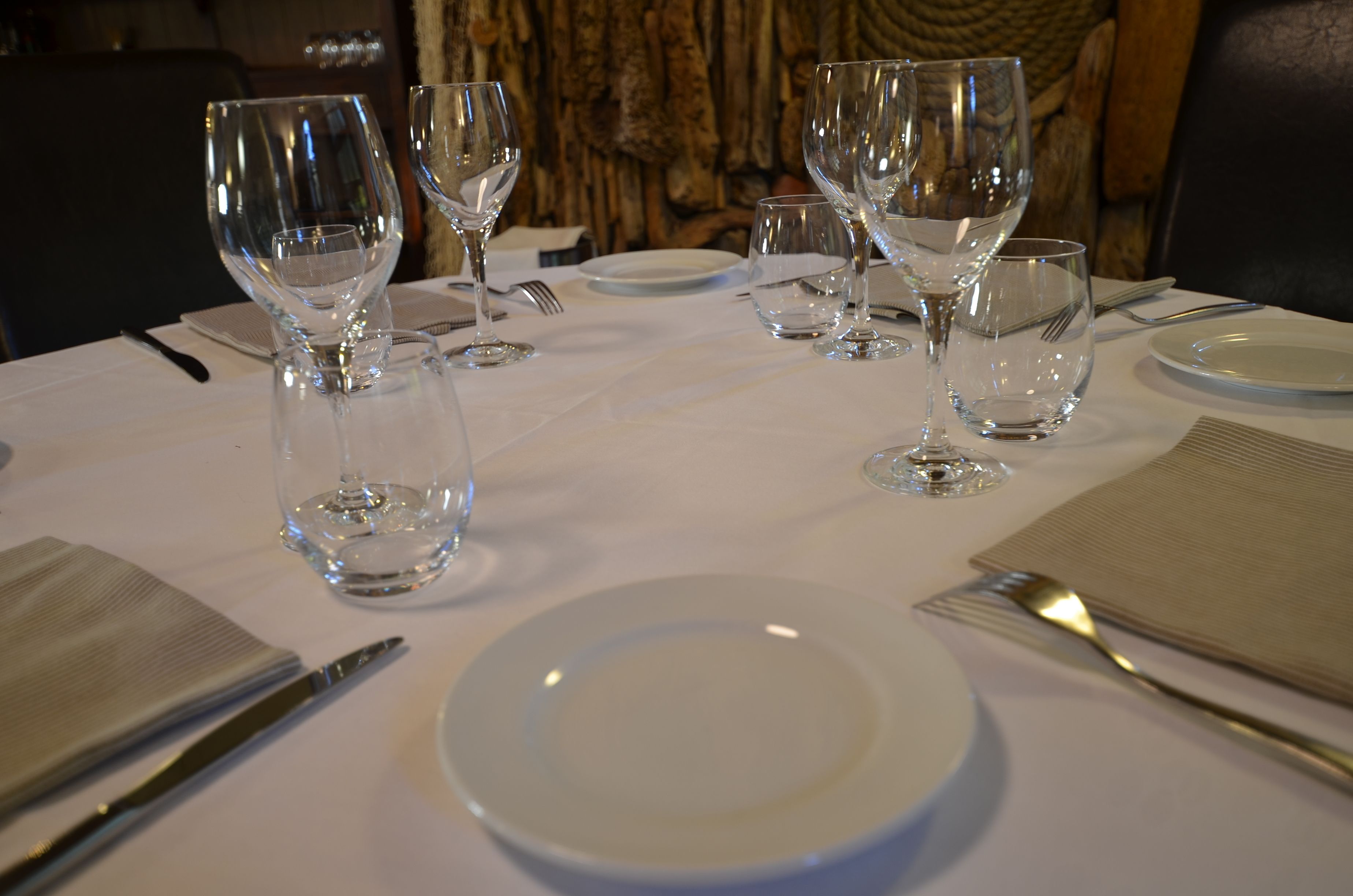 Une table mise avec des verres à vin, des assiettes et des couverts.
