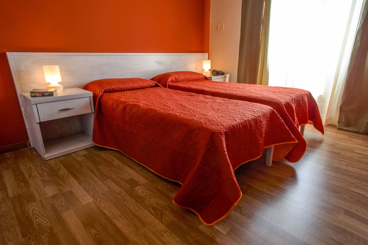 Une chambre d’hôtel avec deux lits, une table de chevet avec une lampe et un plancher en bois.