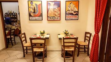 Un comedor con dos mesas, sillas y tres carteles enmarcados en la pared.