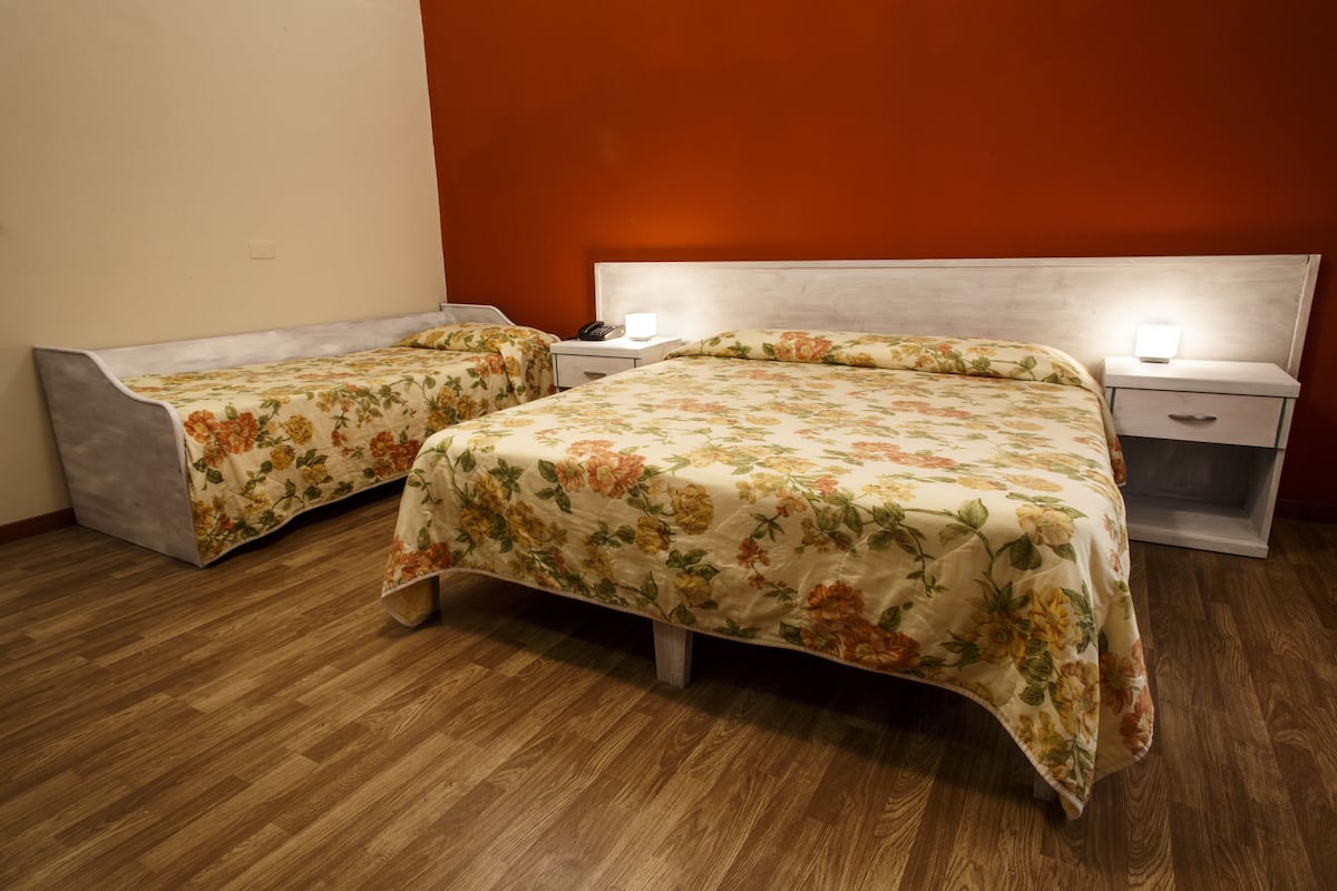 Une chambre à coucher avec deux lits, chacun recouvert d’une couvre-lit à motifs floraux et agrémenté de lampes de chevet.