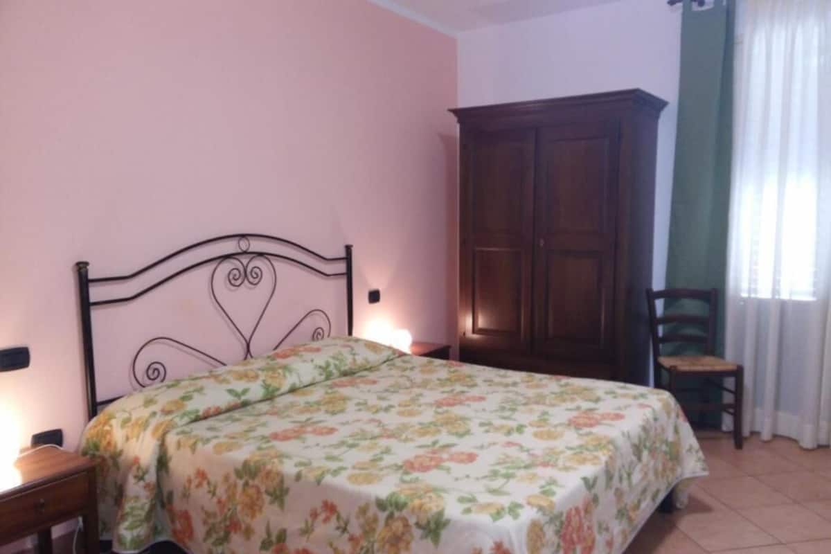 Une chambre à coucher avec un lit, une armoire en bois, une chaise et une table de chevet.