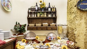 Mesa de buffet com diversos alimentos, uma estante para vinhos e bebidas acima, e uma parede rústica.