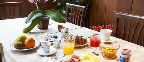 Una mesa de desayuno con diversas opciones de comida, como frutas, pastelería y bebidas.