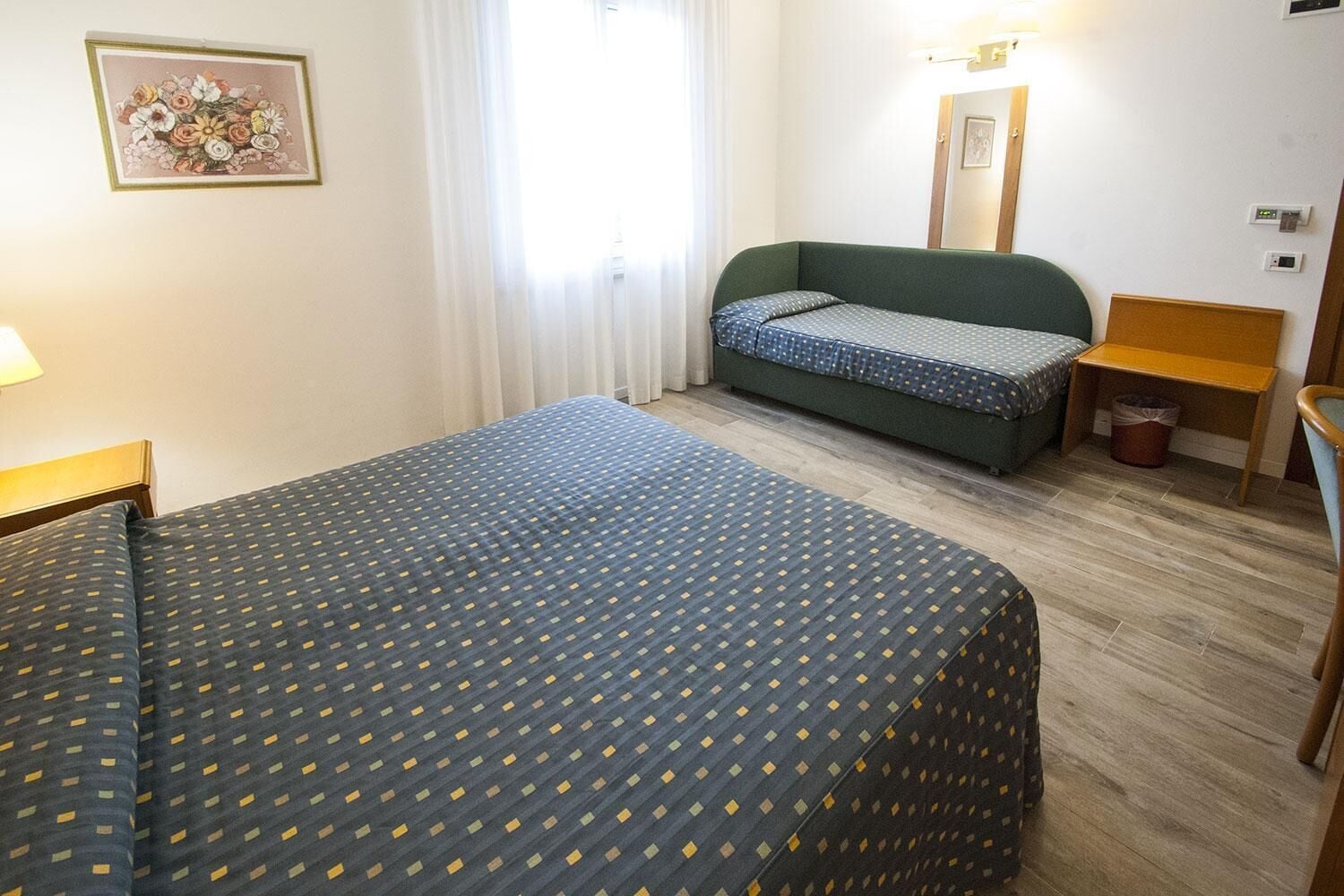 Una habitación de hotel con una cama grande, un sofá, una silla y una mesita.