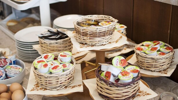 A buffet table with various food items including baskets of yogurt and eggs. - Hotel Italia (Ravenna)