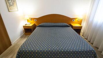 Una camera d'albergo con un letto, due comodini e una testiera.