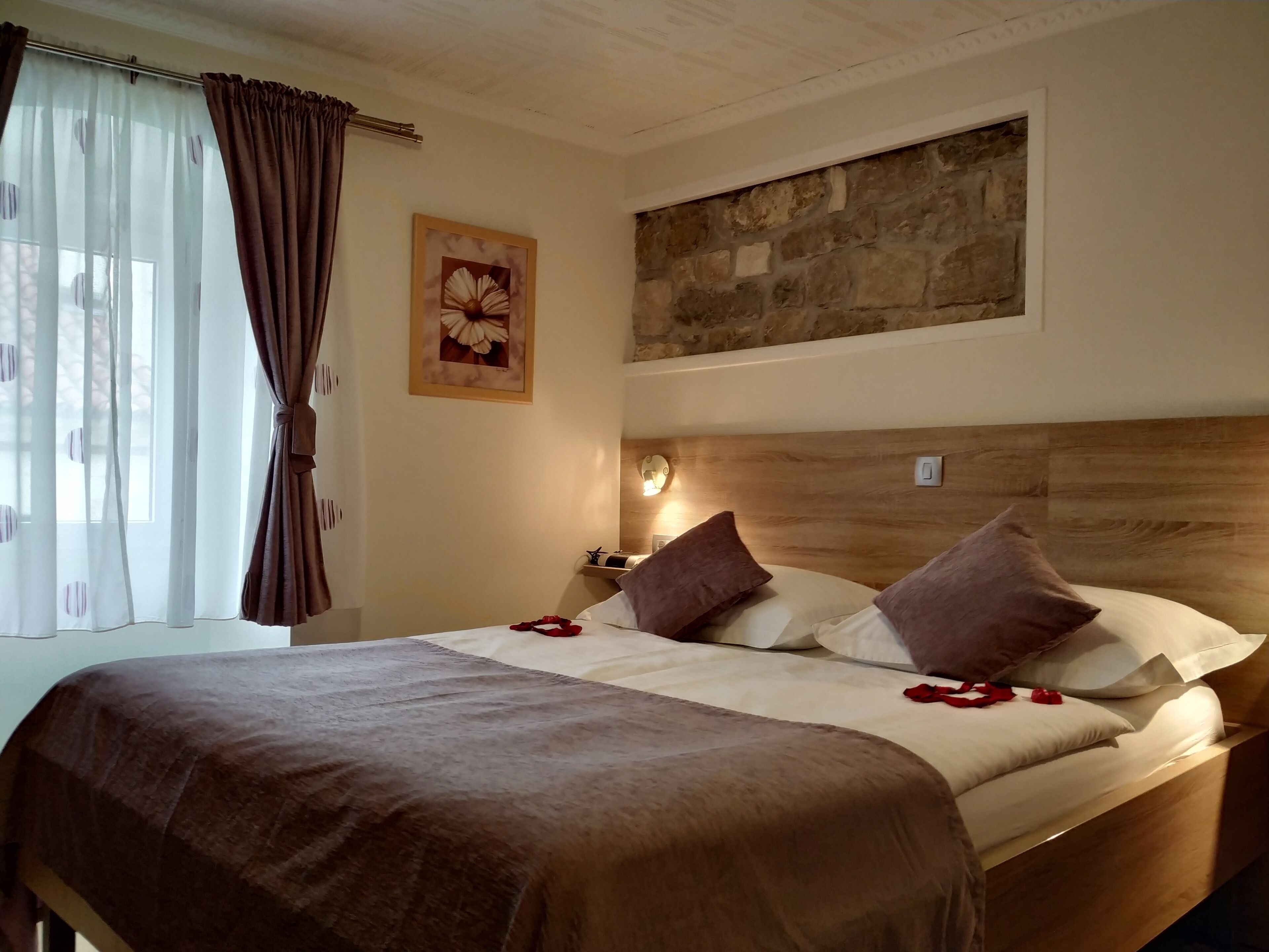 A neatly made bed with a brown blanket, two pillows, and a wooden headboard.