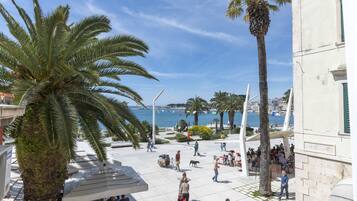 A public square with palm trees, outdoor seating, and a view of the sea.