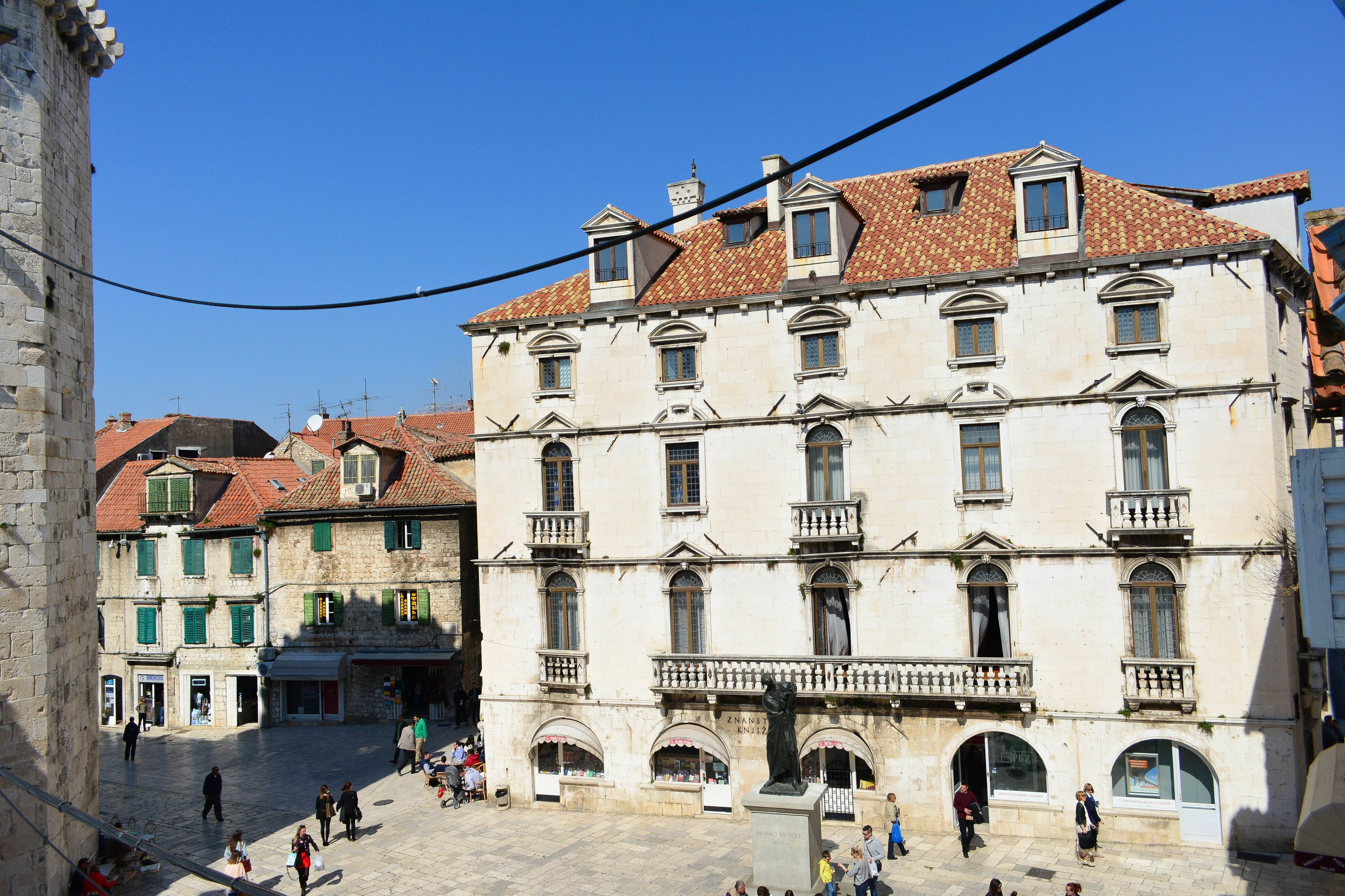 A historic building with multiple stories, arched windows, and a central statue.