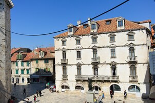 A historic building with multiple stories, arched windows, and a central statue.