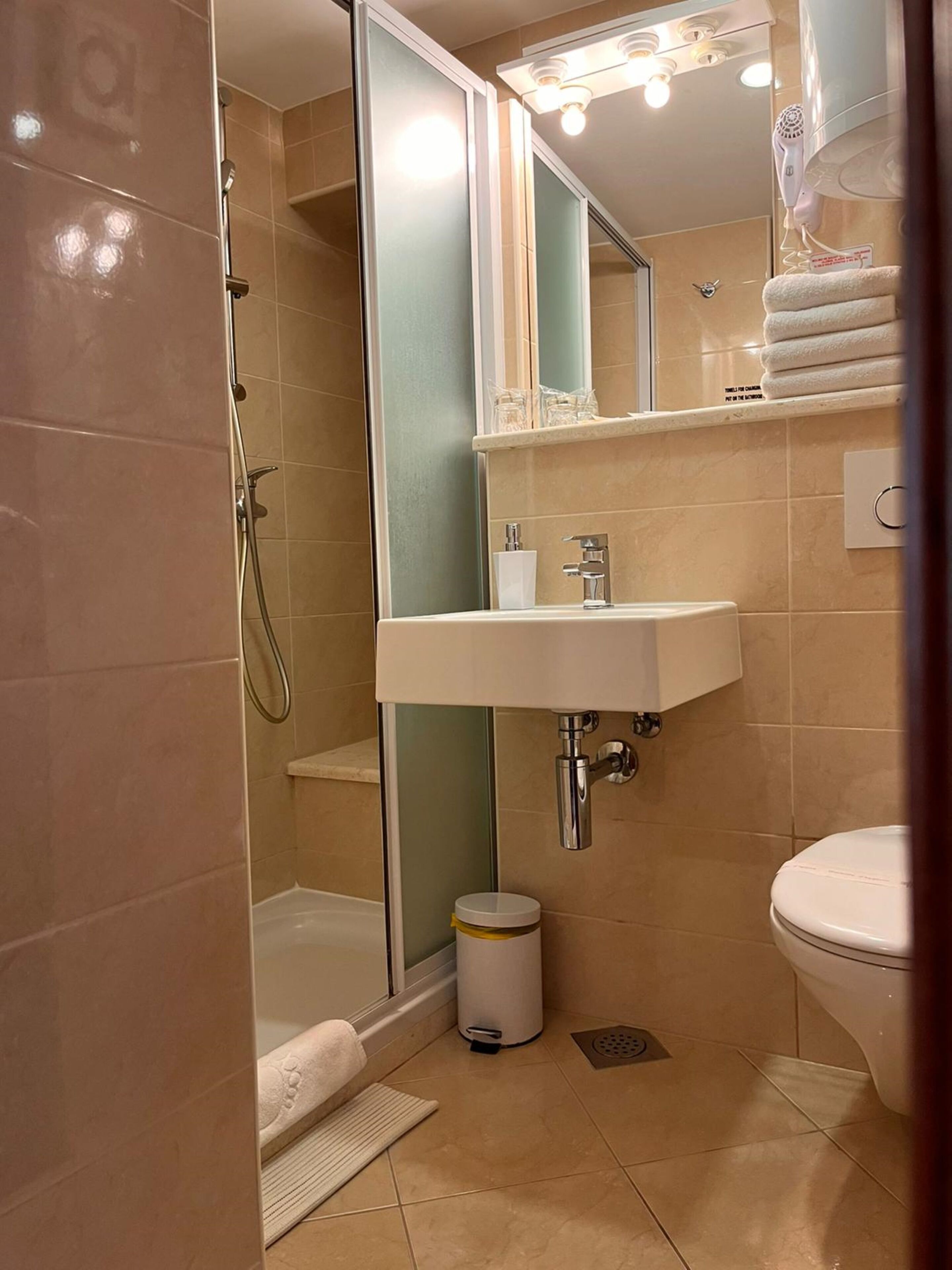 Ein modernes Badezimmer mit einer Duschkabine, einem weißen Waschbecken und einer Toilette.