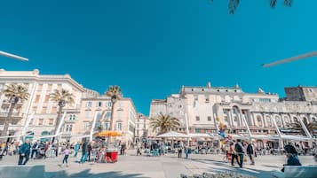 A bustling square with historic buildings, a central fountain, and outdoor seating areas.