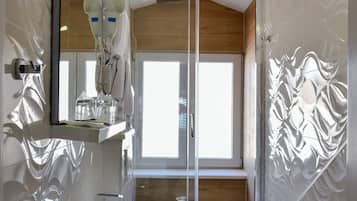 A modern bathroom with a white sink, mirror, and shower enclosure.