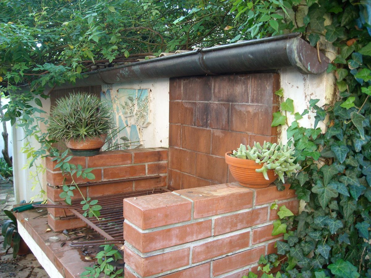 A brick structure with a metal gutter and two potted plants.