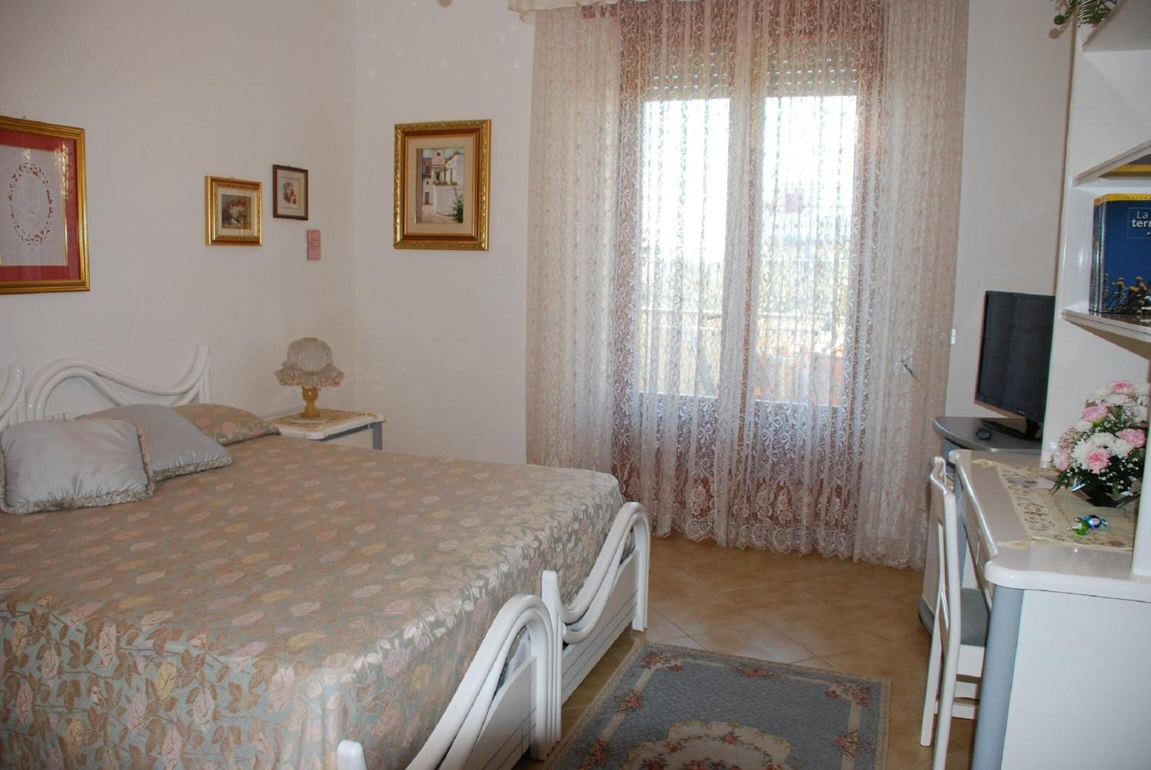 Ein Schlafzimmer mit Bett, Schreibtisch, Stuhl und Fernseher.