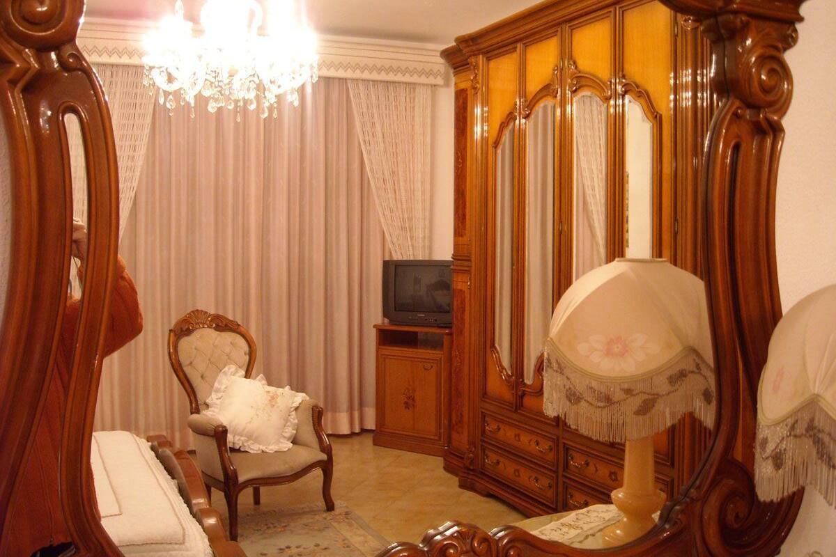 Una habitación con un espejo grande, un armario de madera, un televisor y una silla.