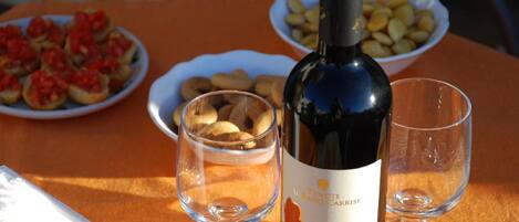 A bottle of wine, two glasses, and plates of food on a table.