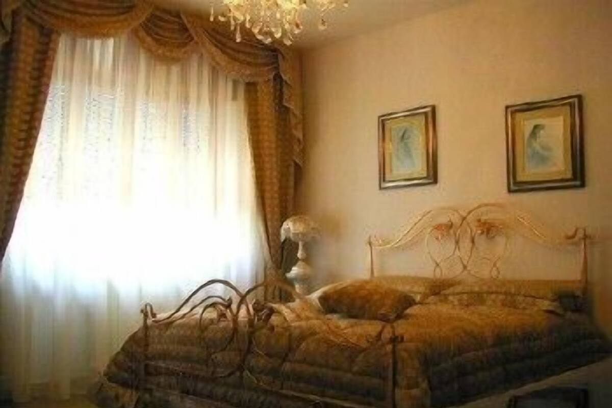 Un dormitorio con cama, cortinas y dos cuadros en la pared.