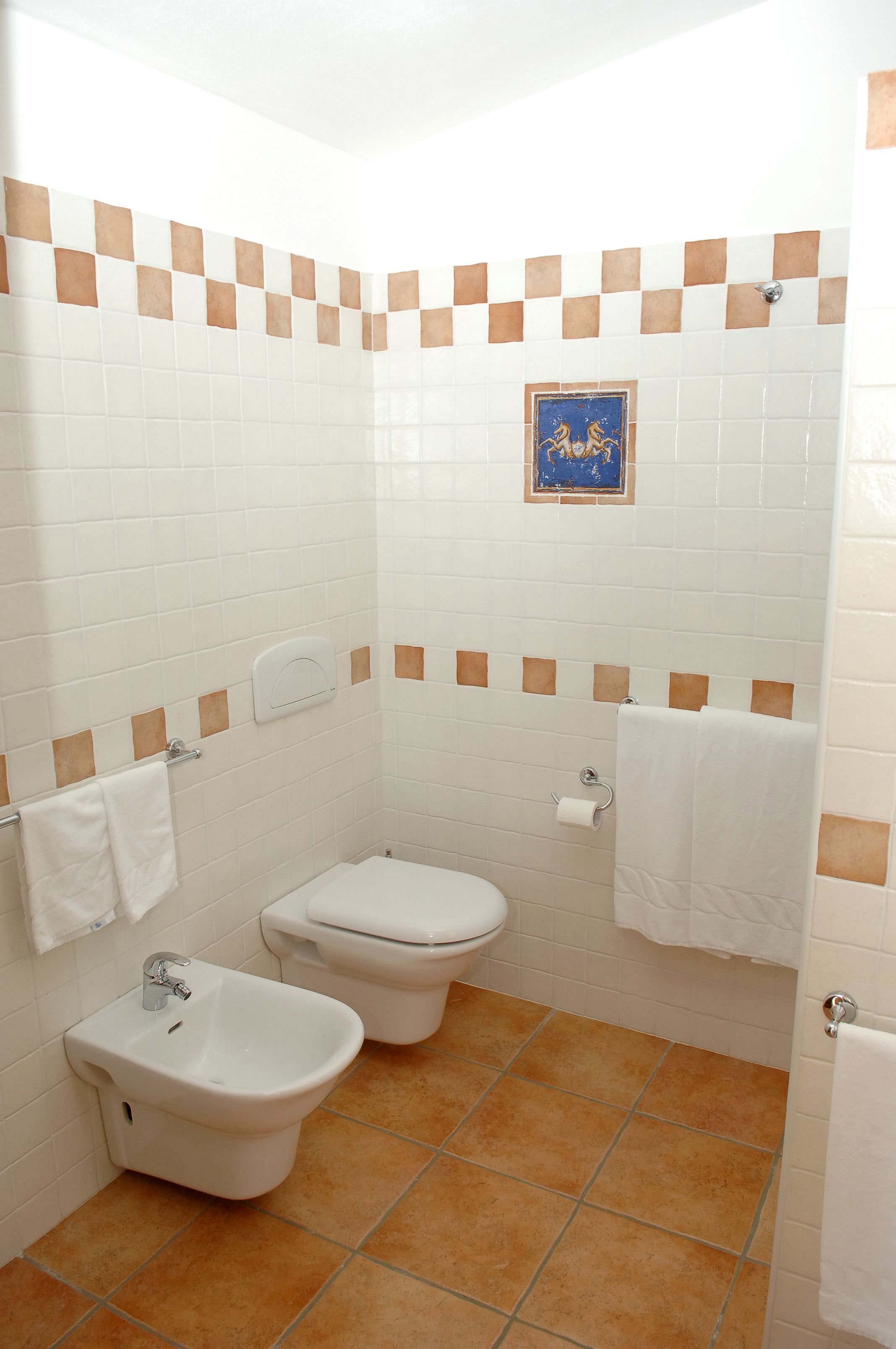 Un baño con bidé, inodoro y perchero para toallas.