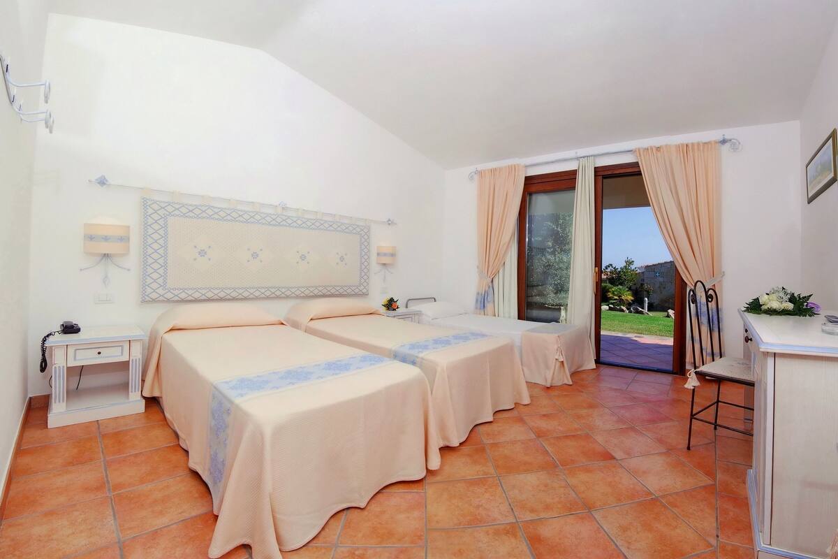 A hotel room with two beds, a desk, a chair, a telephone, and a window with curtains.