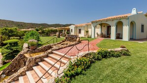 Una villa de estilo mediterráneo con una escalera de piedra, un patio y un jardín bien cuidado.