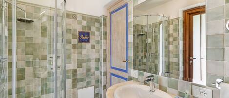 A modern bathroom with a glass-enclosed shower, a large sink, and a mirror.