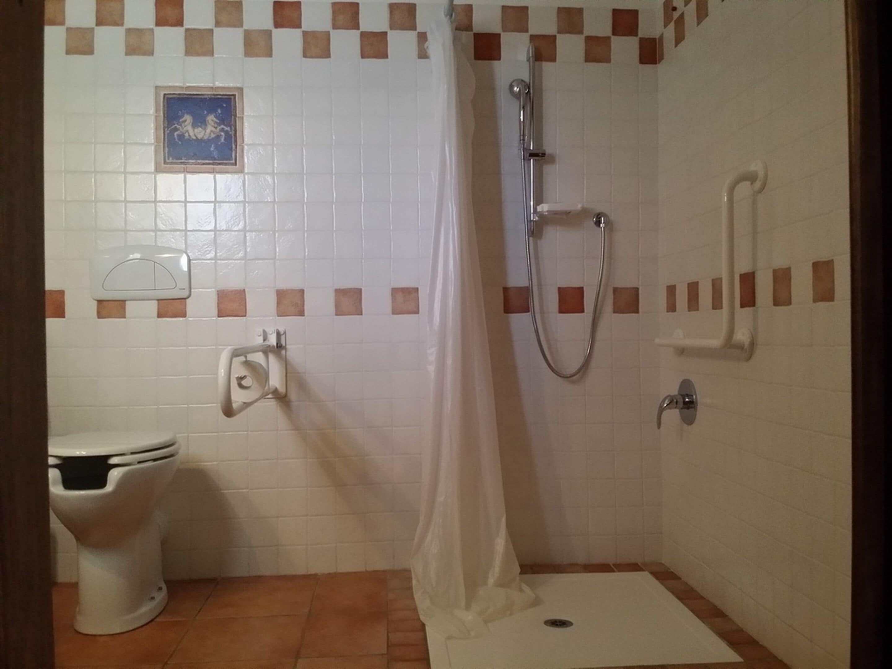 A small bathroom with a toilet, a shower, and a towel rack.