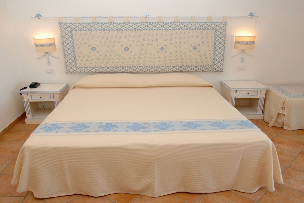 A neatly arranged bedroom with a large bed, two bedside tables, and a small bedside table.