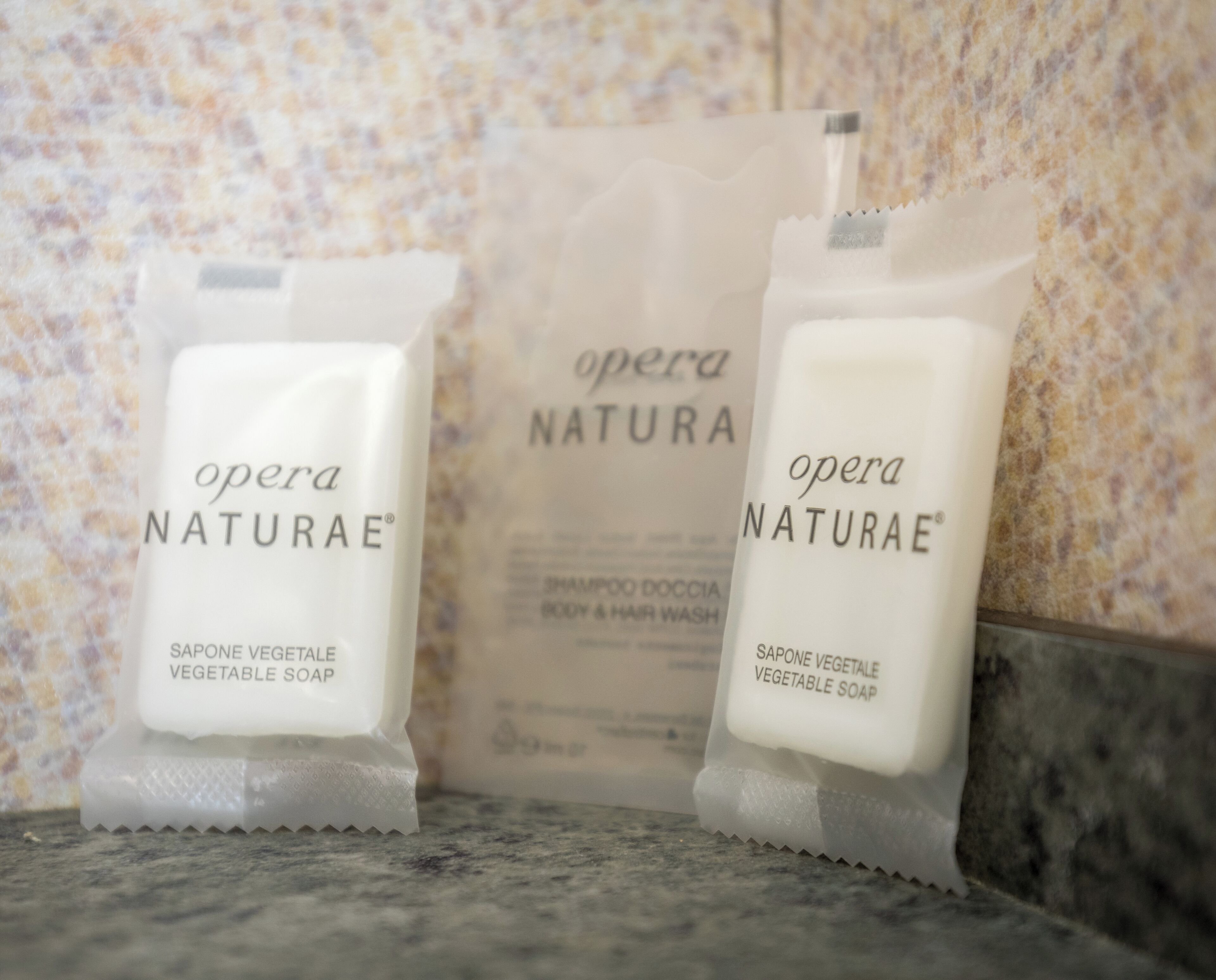 Two bottles of opera Naturae vegetable soap on a marble surface.