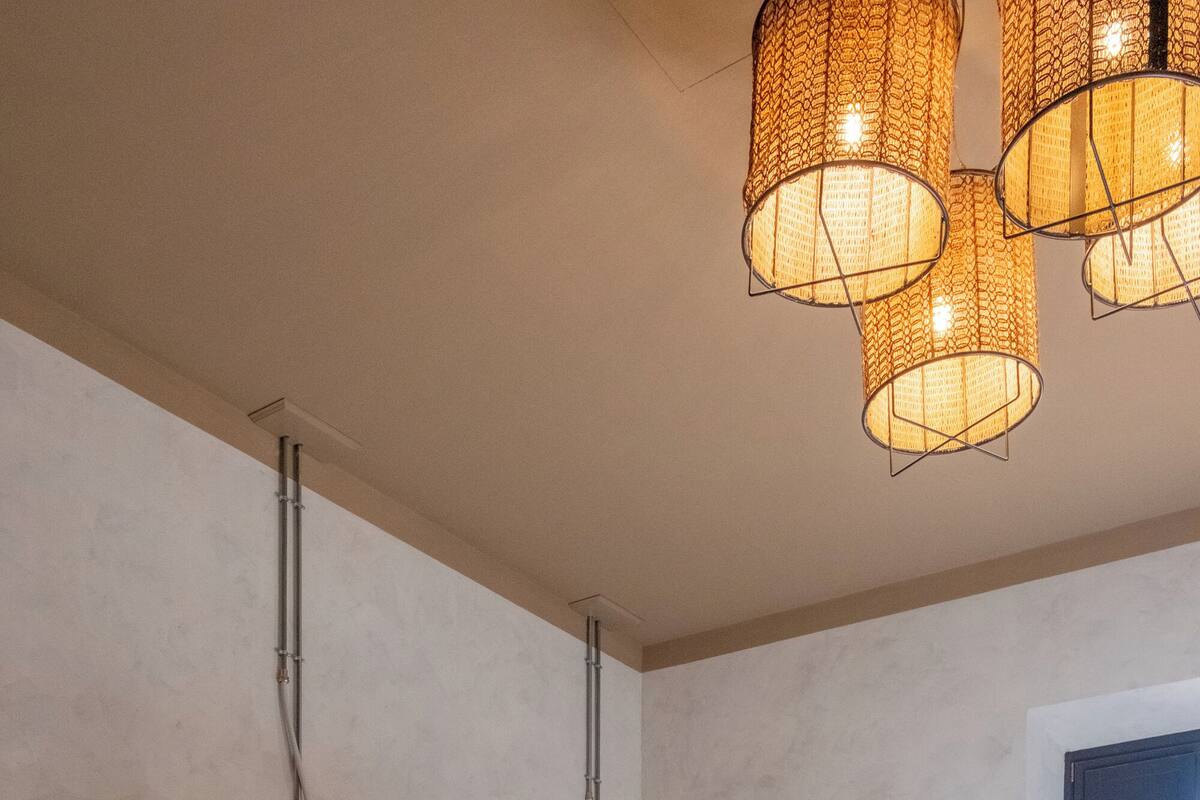 A dormitory room with bunk beds, a tiled floor, and a hanging light fixture.