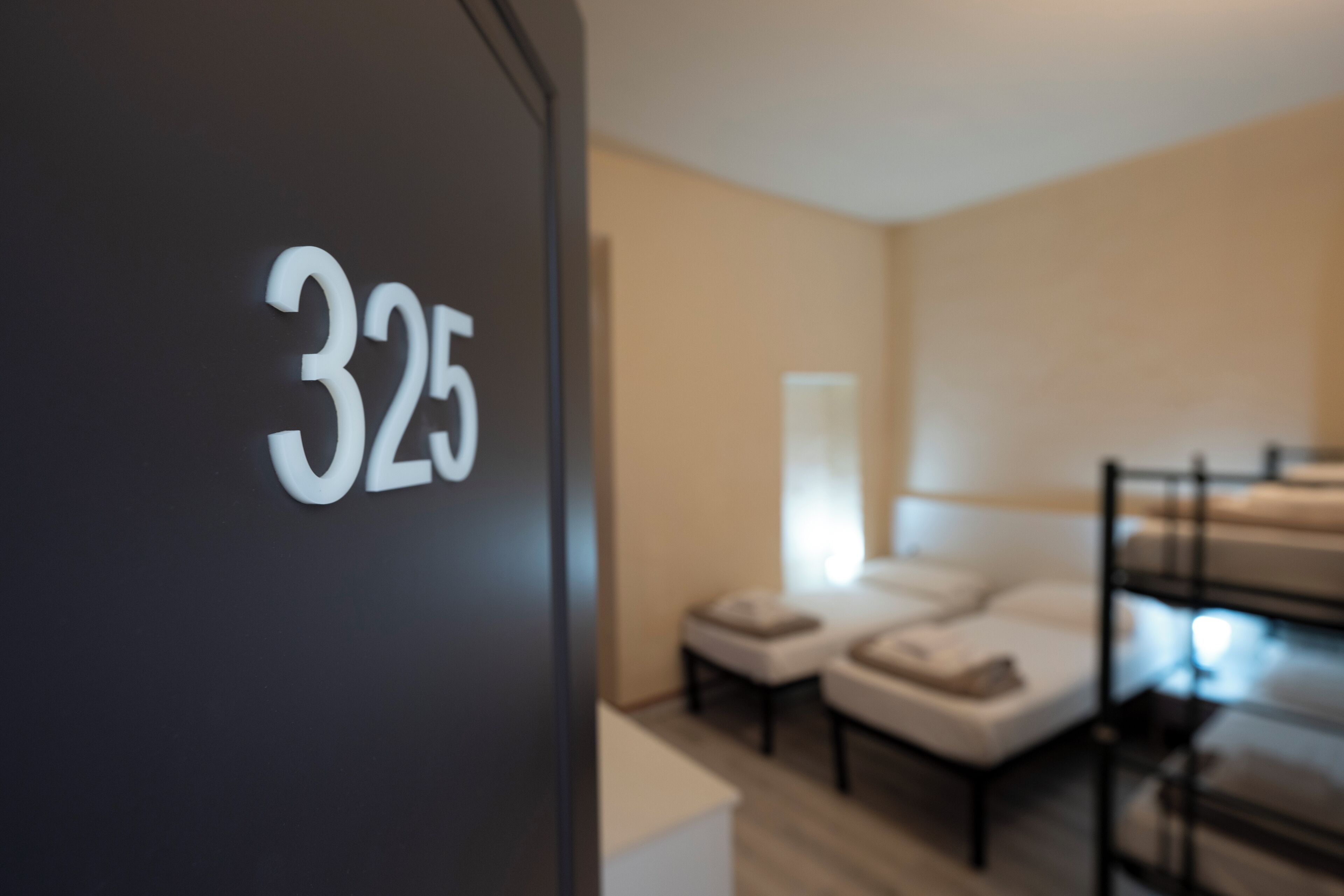 Ein Zimmer mit einem Etagenbett, einer kleinen Sitzecke und der Nummer 325 an der Wand.