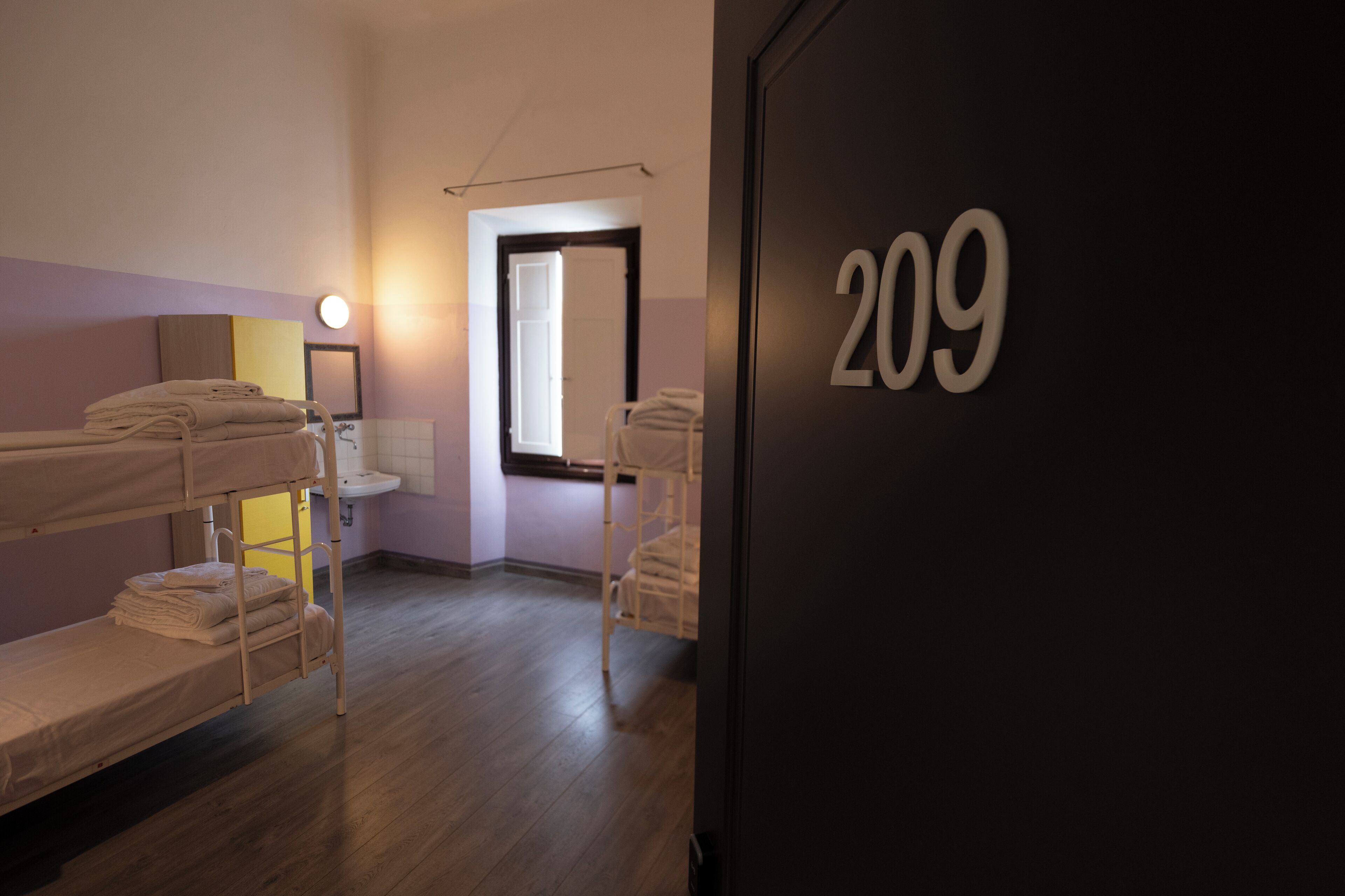 Una habitación con literas, un lavamanos y una puerta con el número 209.