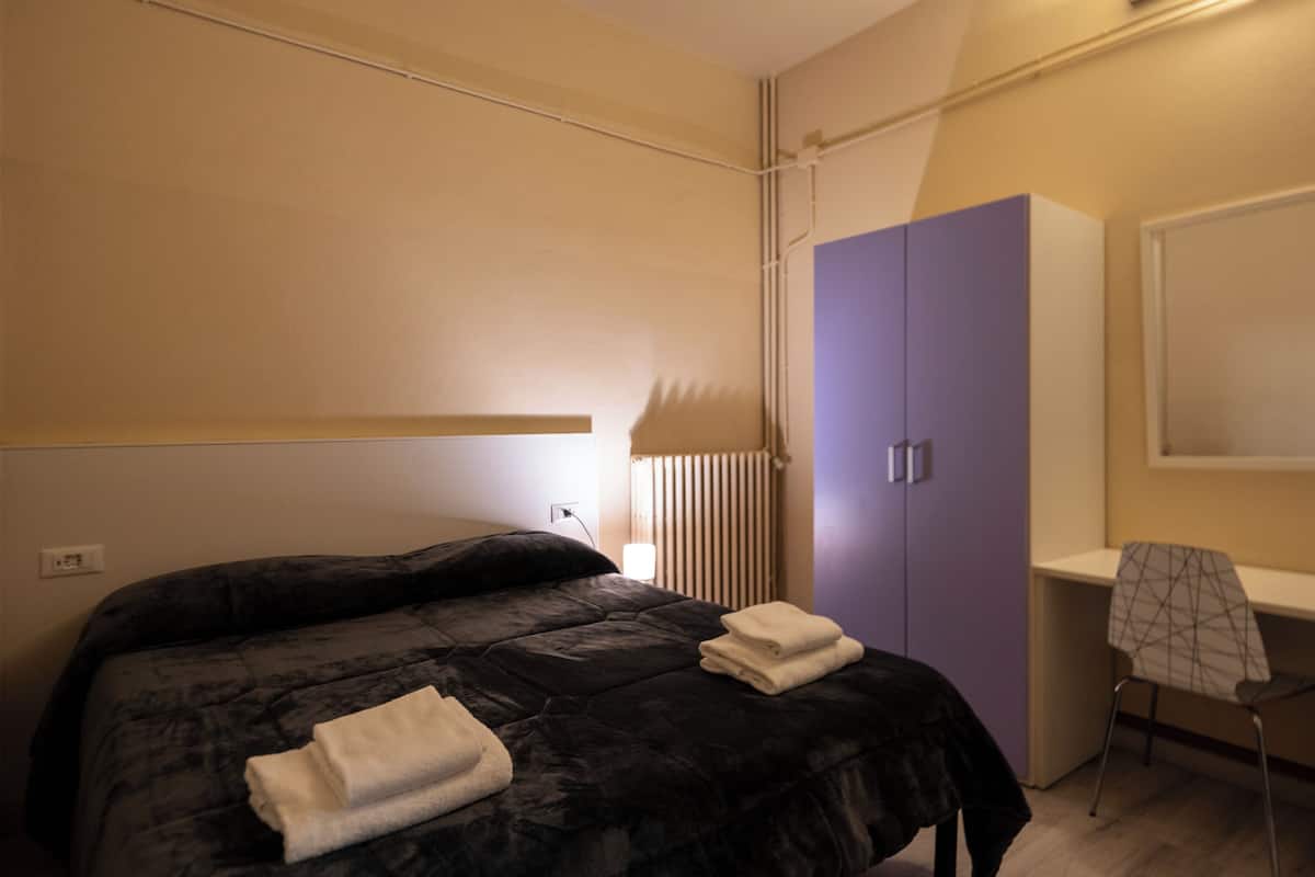 A bedroom with a bed, a wardrobe, and a desk.