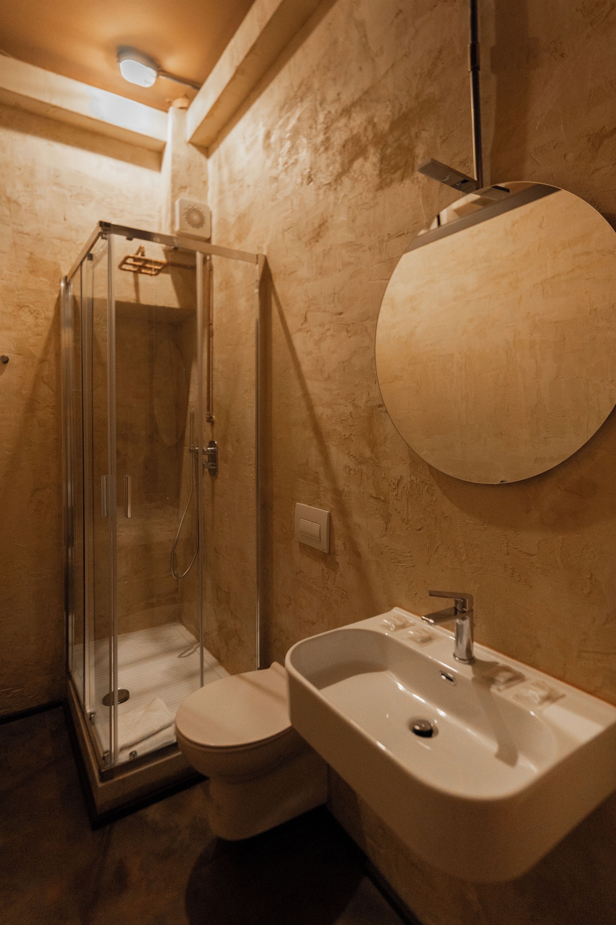 A bathroom with a glass-enclosed shower, a toilet, and a sink with a mirror above it.