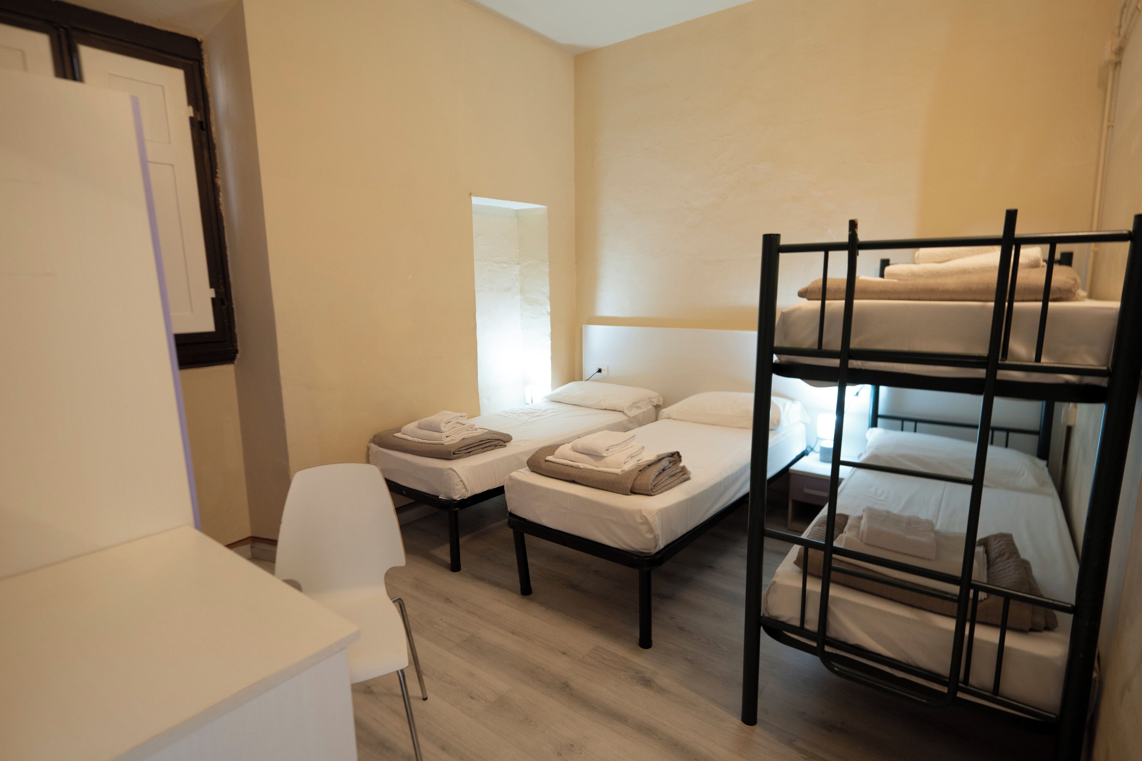Una habitació amb llits superposats, un escriptori i una cadira.