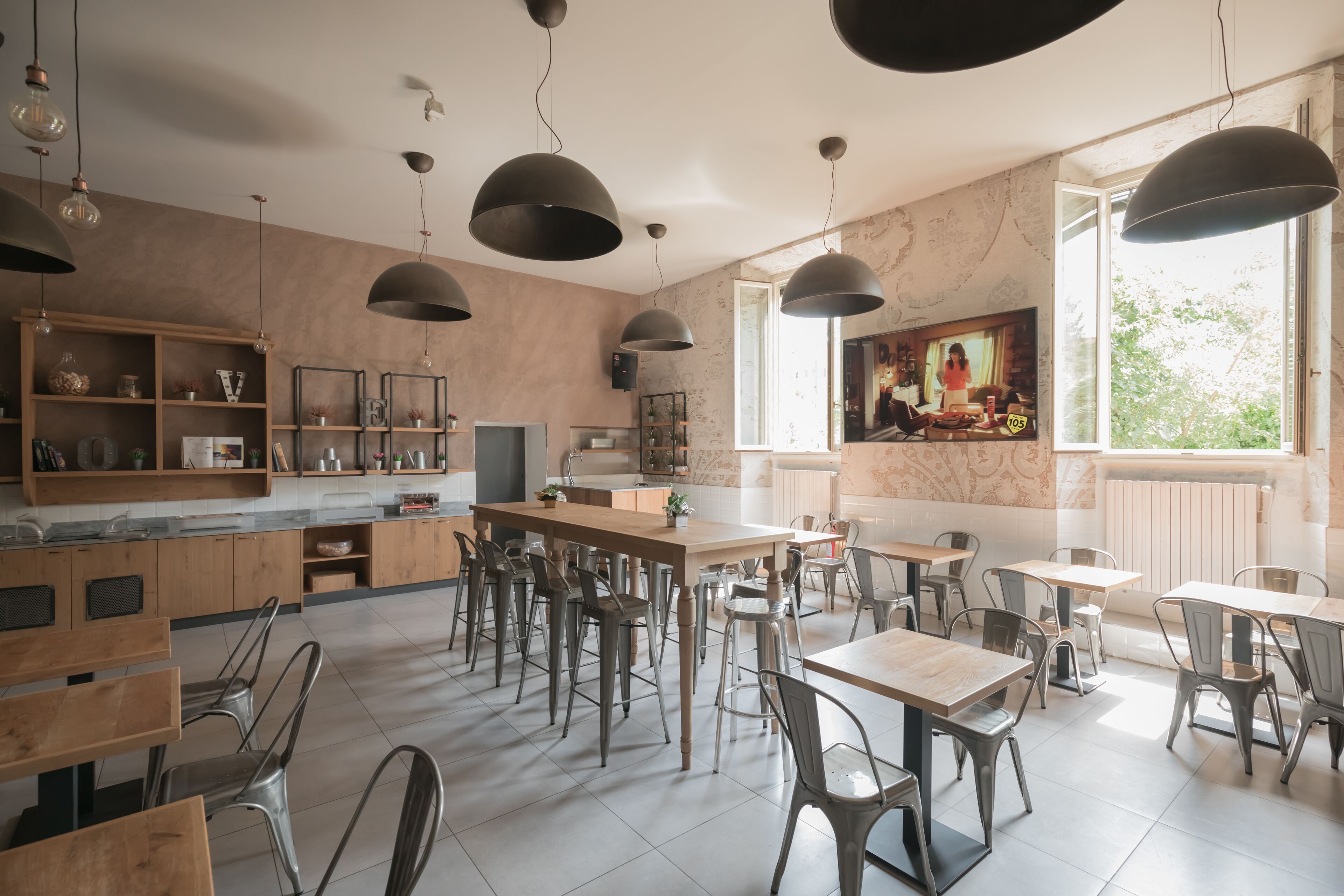 A modern cafe with a central bar area, multiple seating options including bar stools and tables, and pendant lighting.