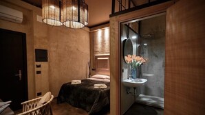 A compact bedroom with a bed, a chair, and a bathroom with a sink and shower. - Ostello 7 Santi (Florence)