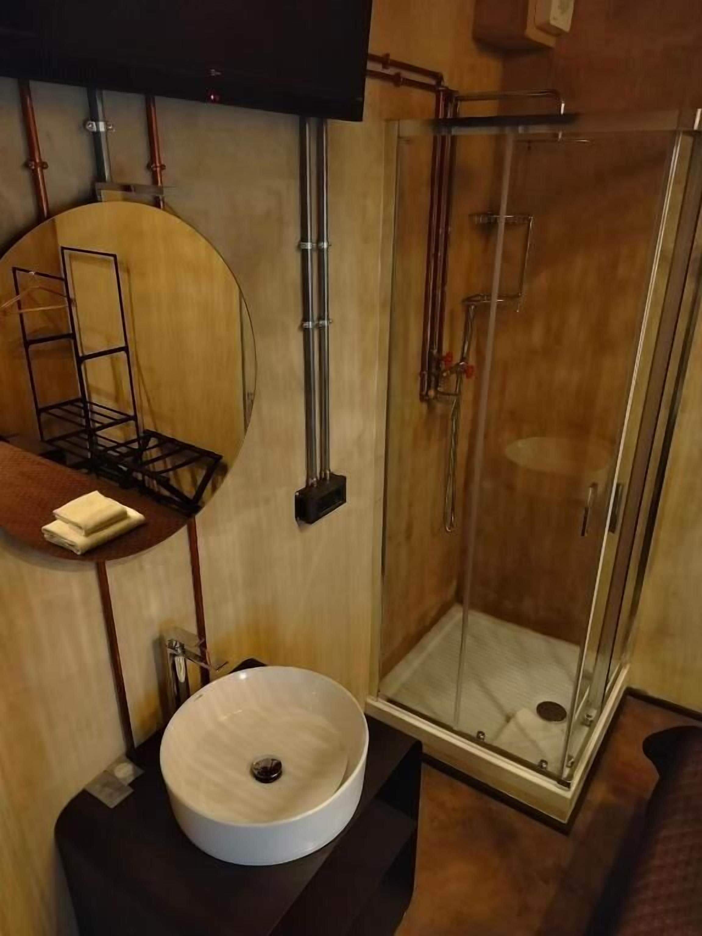 Ein Badezimmer mit einem runden Waschbecken, einer Duschkabine aus Glas und einem Handtuchhalter.