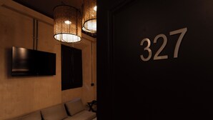 A modern interior with a sofa, a flat-screen TV, and a number '327' on the wall. - Ostello 7 Santi (Florence)
