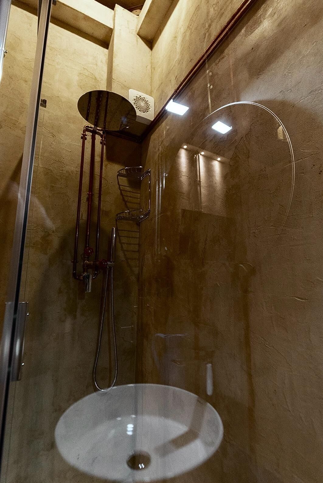 A shower with a glass enclosure, a sink, and a towel rack.